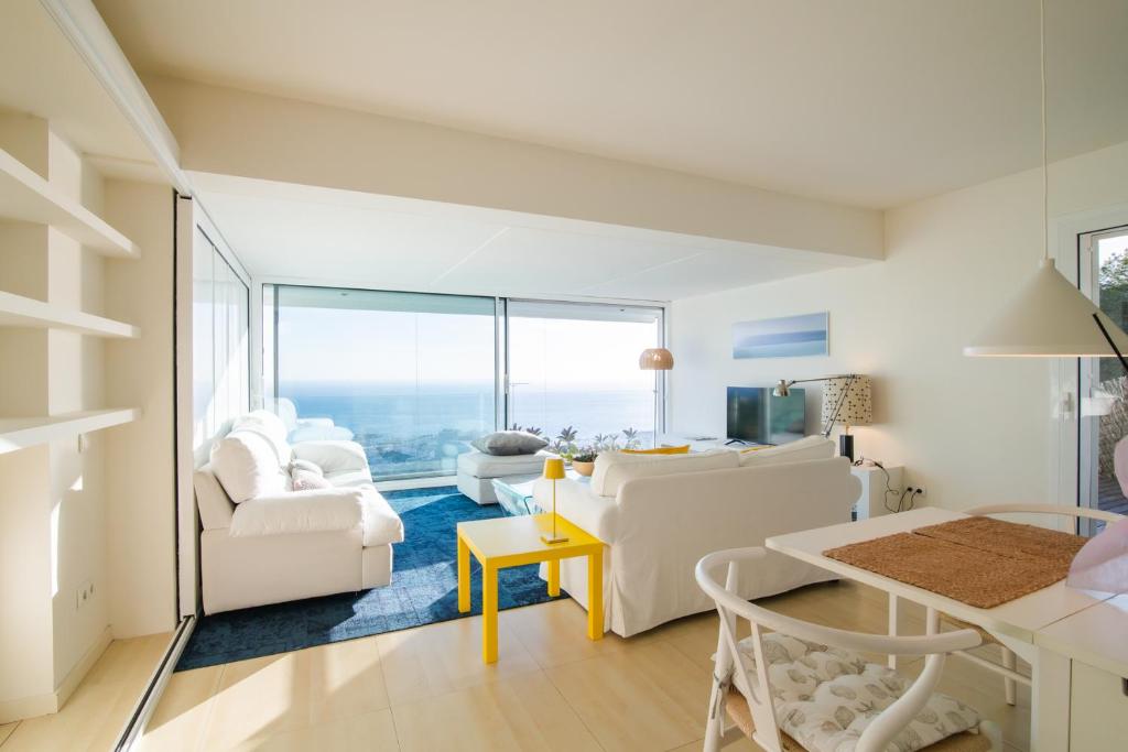 シッチェスにあるSitges Suites Bの白い家具付きのリビングルームが備わり、海の景色を望めます。