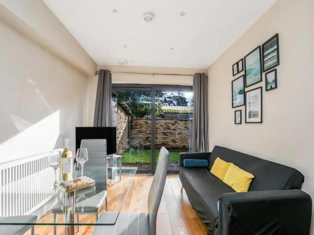 uma sala de estar com um sofá preto e uma mesa de vidro em Pass the Keys Ealing Queen of the Suburbs 2BD Apartment em Londres