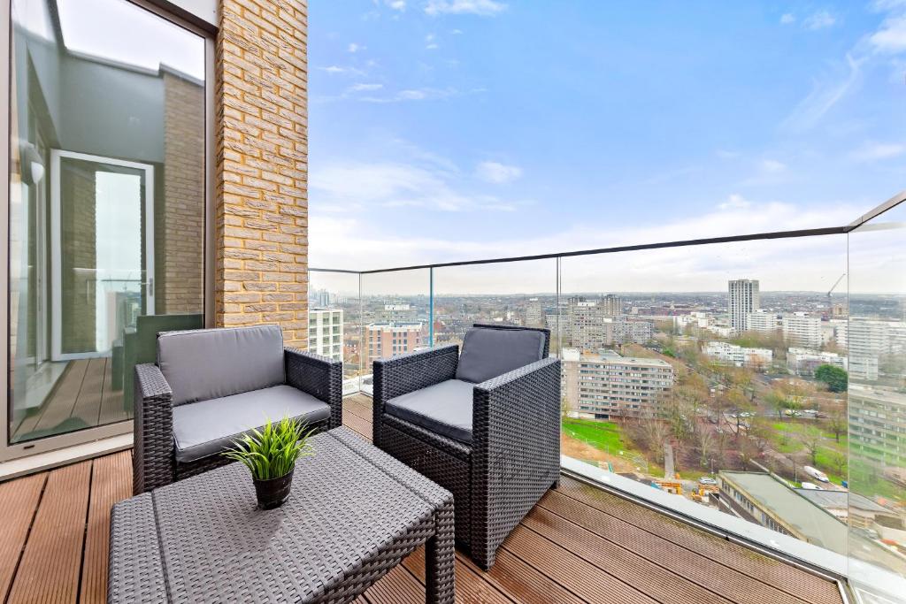 a balcony with two chairs and a table on a balcony at Battersea Penthouse Sleep 9 WH in London