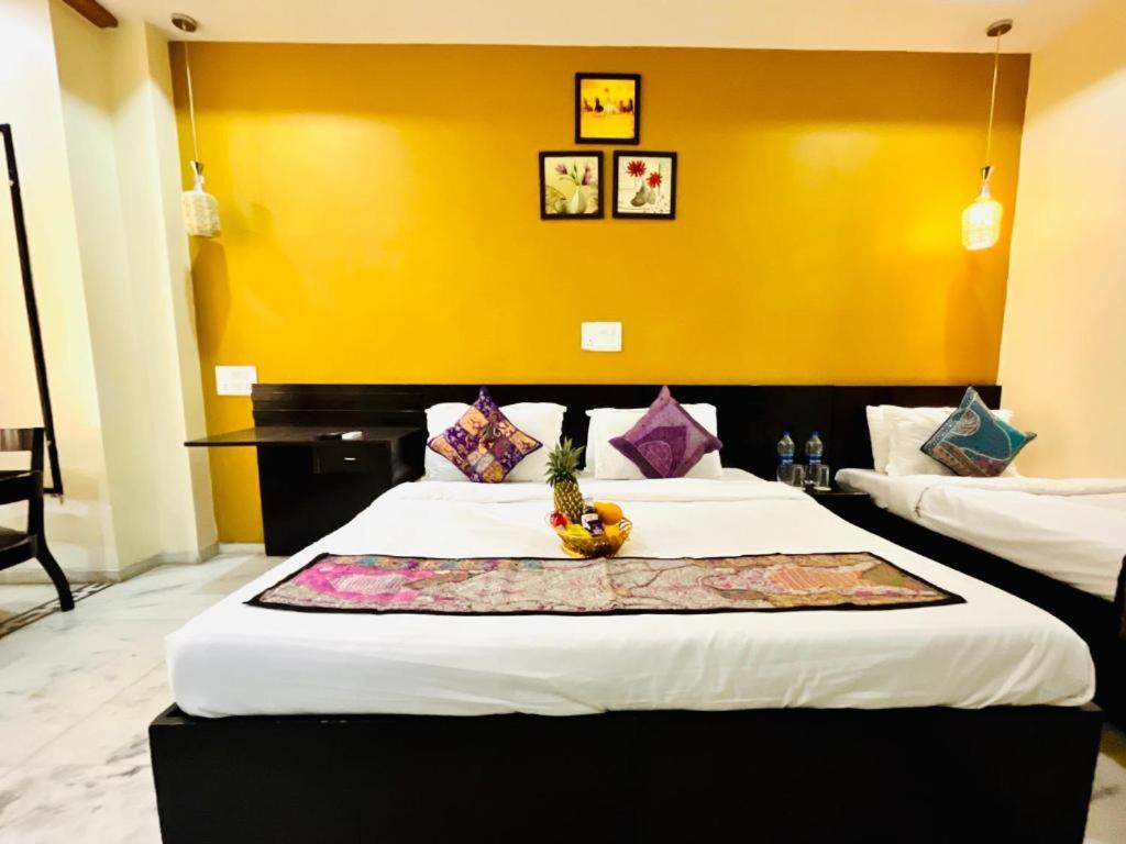 a bedroom with two beds and a yellow wall at Hotel GVS-24 CLUB, Rooftop Cafe! swimming pool! Karaoke Music! in Udaipur