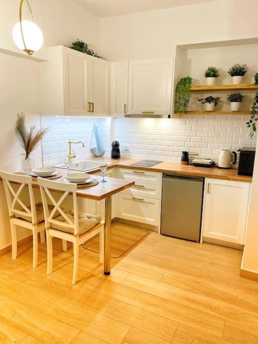 kuchnia z białymi szafkami oraz stołem i krzesłami w obiekcie Διαμέρισμα στην Καλλιθέα w Atenach