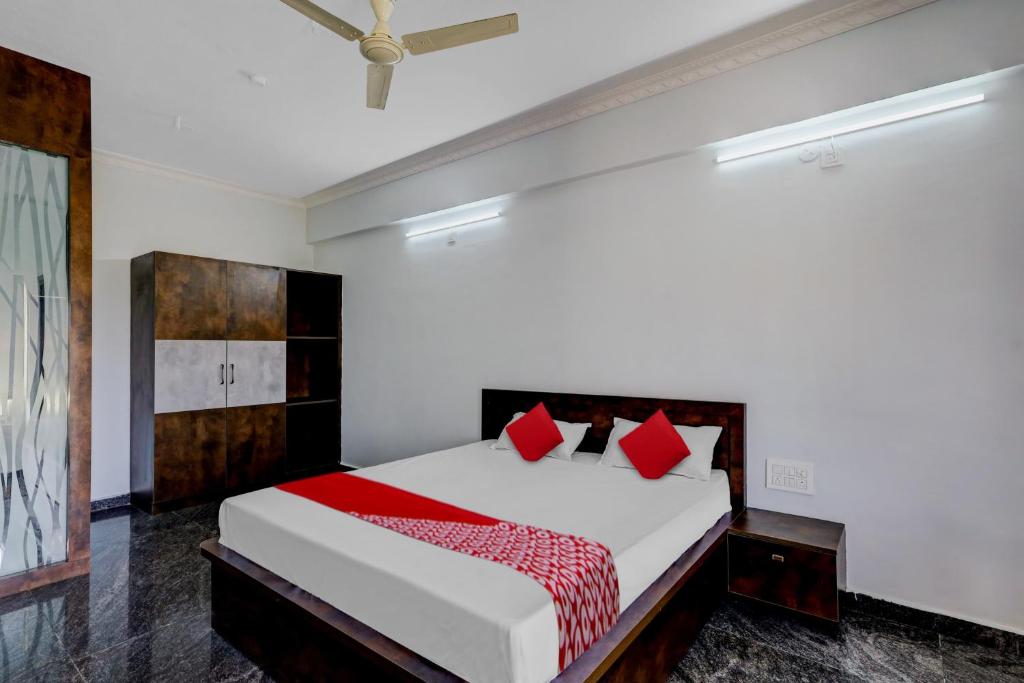 1 dormitorio con 1 cama grande con almohadas rojas en OYO JDR GARDENS, en Tirupati