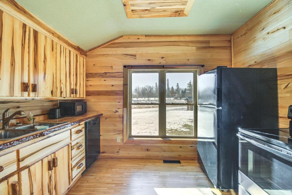 eine Küche mit Holzwänden und einem schwarzen Kühlschrank in der Unterkunft Pet-Friendly Minnesota Abode Near Golfing and Hiking 