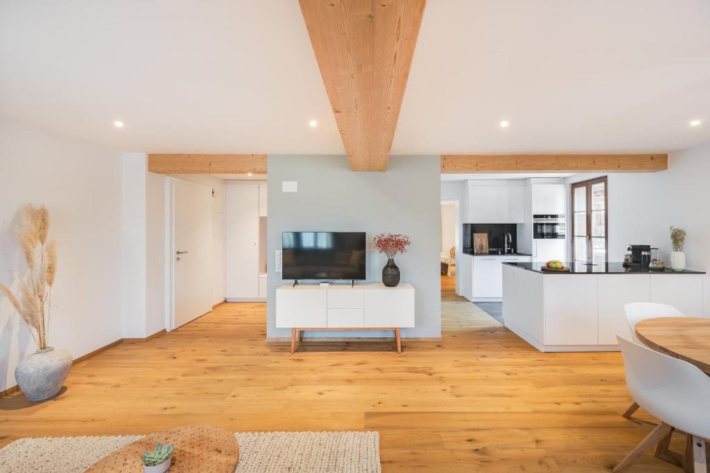 uma cozinha e sala de estar com paredes brancas e pisos de madeira em Bijou Lake Side - mit Seesicht und Privatstrand em Faulensee