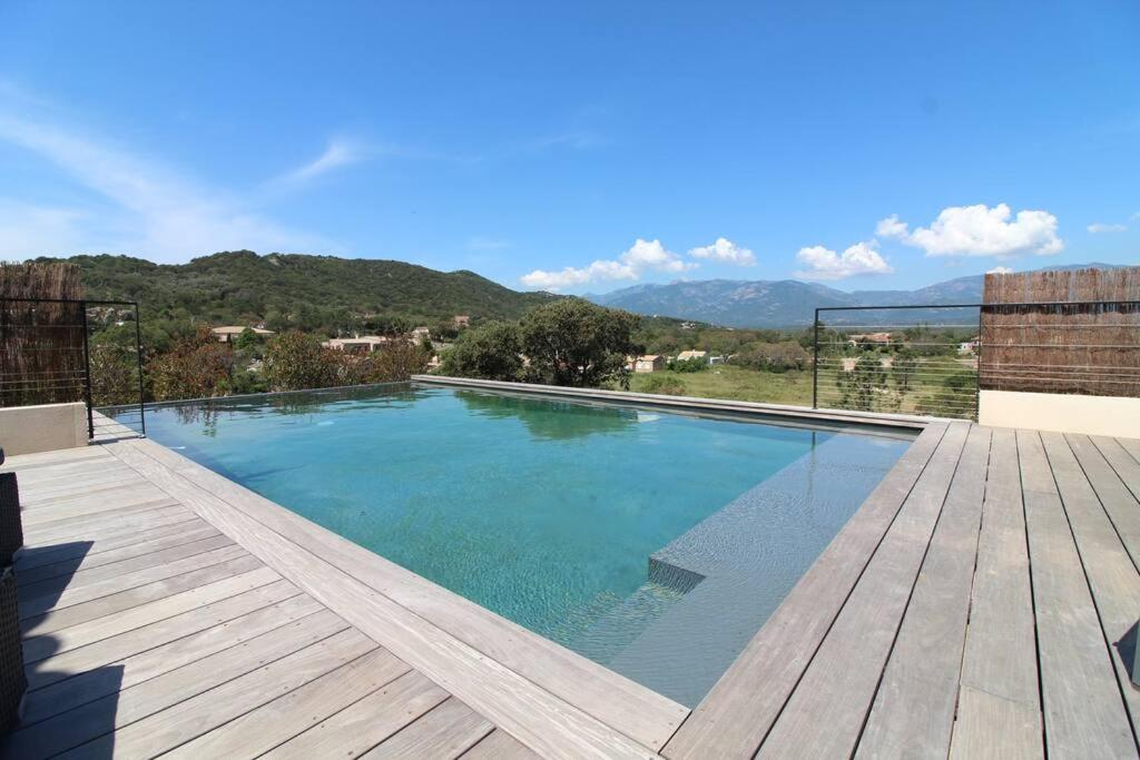 une grande piscine avec une terrasse en bois dans l'établissement Villa Porra avec piscine 8 pers vue montagne, à Porto-Vecchio