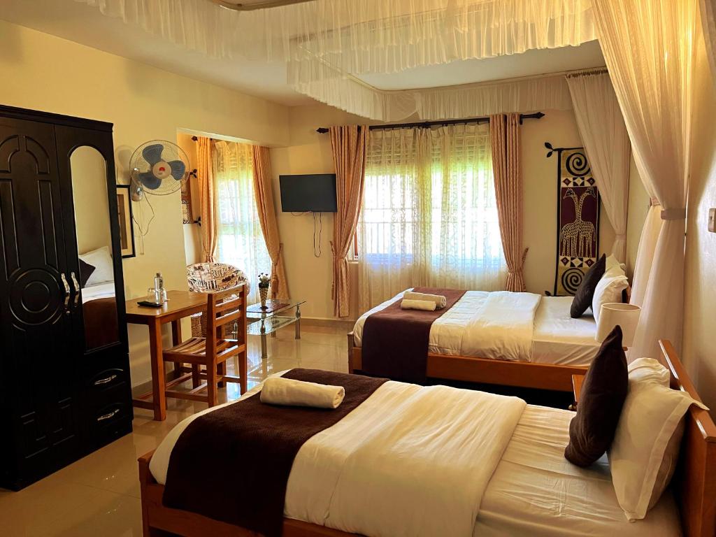 エンテベにあるSunset Hotel Entebbeのベッド2台、テーブル、デスクが備わる客室です。