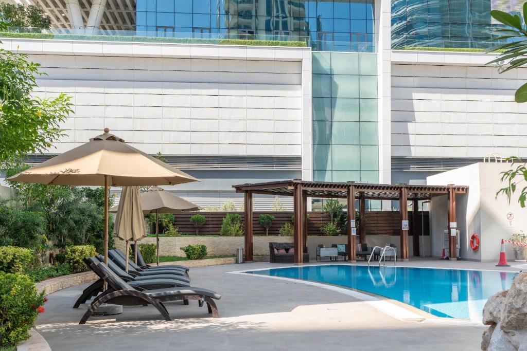 a pool with chairs and an umbrella next to a building at Dubai Marina Next to Metro and JBR Beach - CityApartmentStay in Dubai