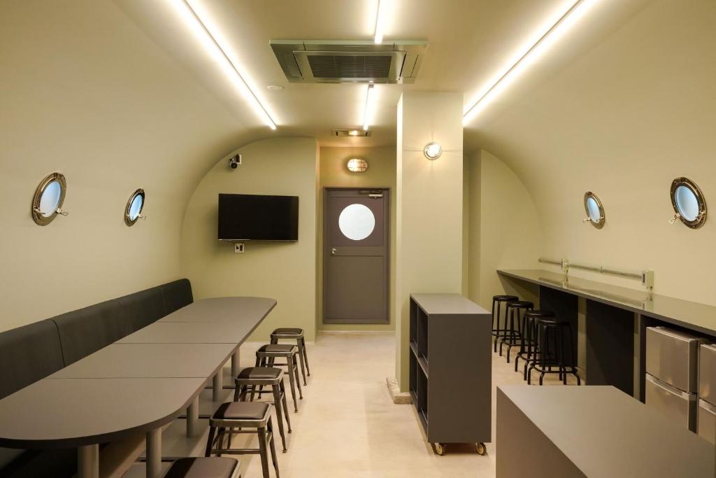 een wachtkamer met tafels en stoelen en een tv bij Red Submarine in Kure