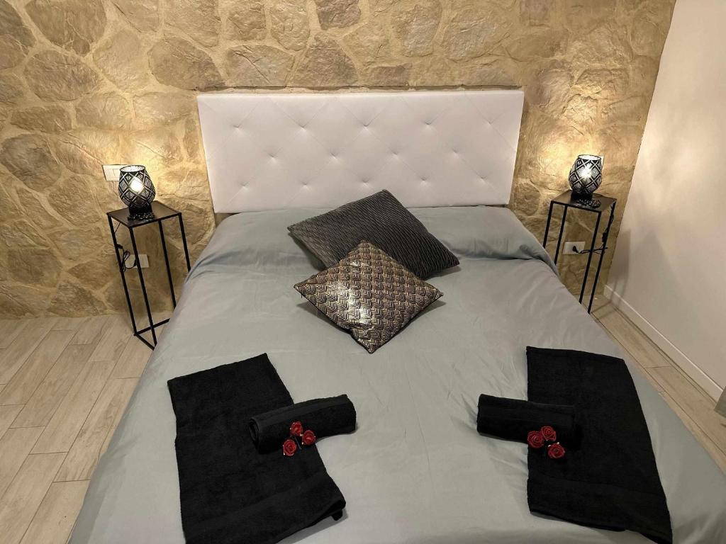 a bed with black pillows and red flowers on it at Langolo di laura borgo roma destiny home 3 in Verona