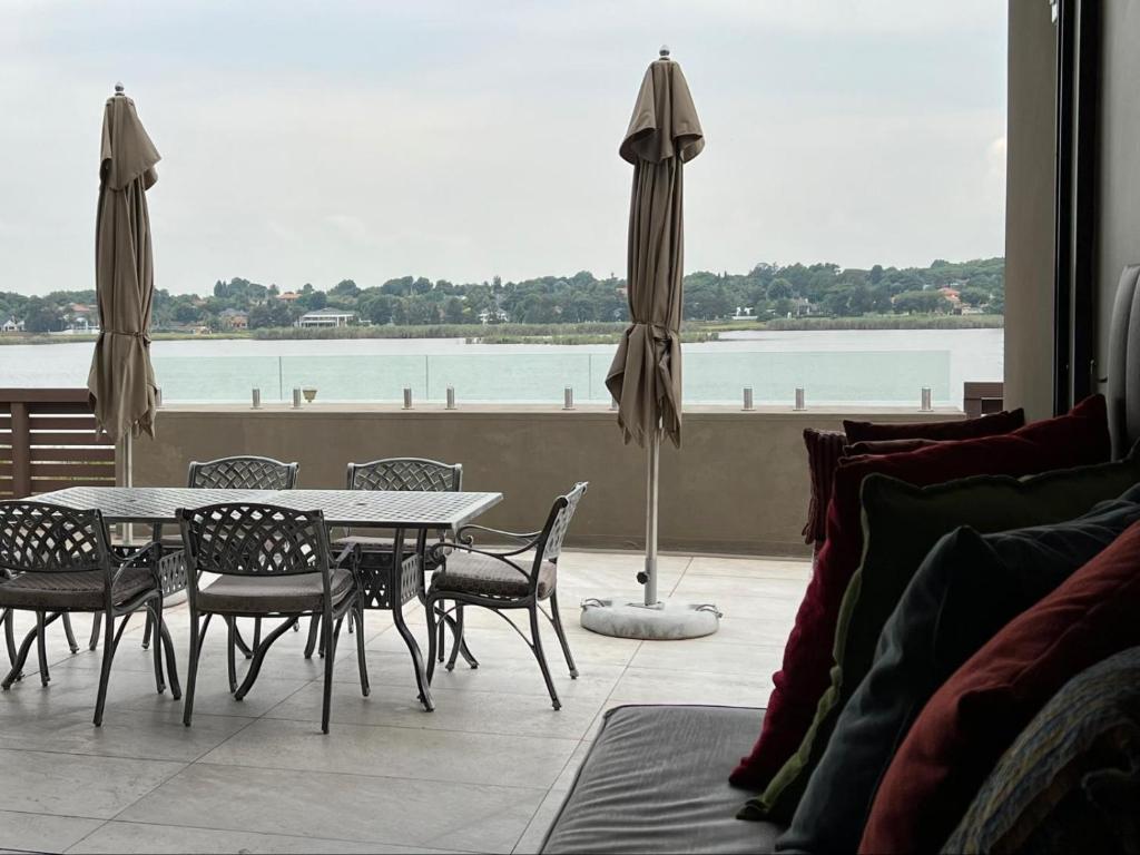un patio con mesa, sillas y sombrilla en One O Eight Boutique Hotel, en Benoni