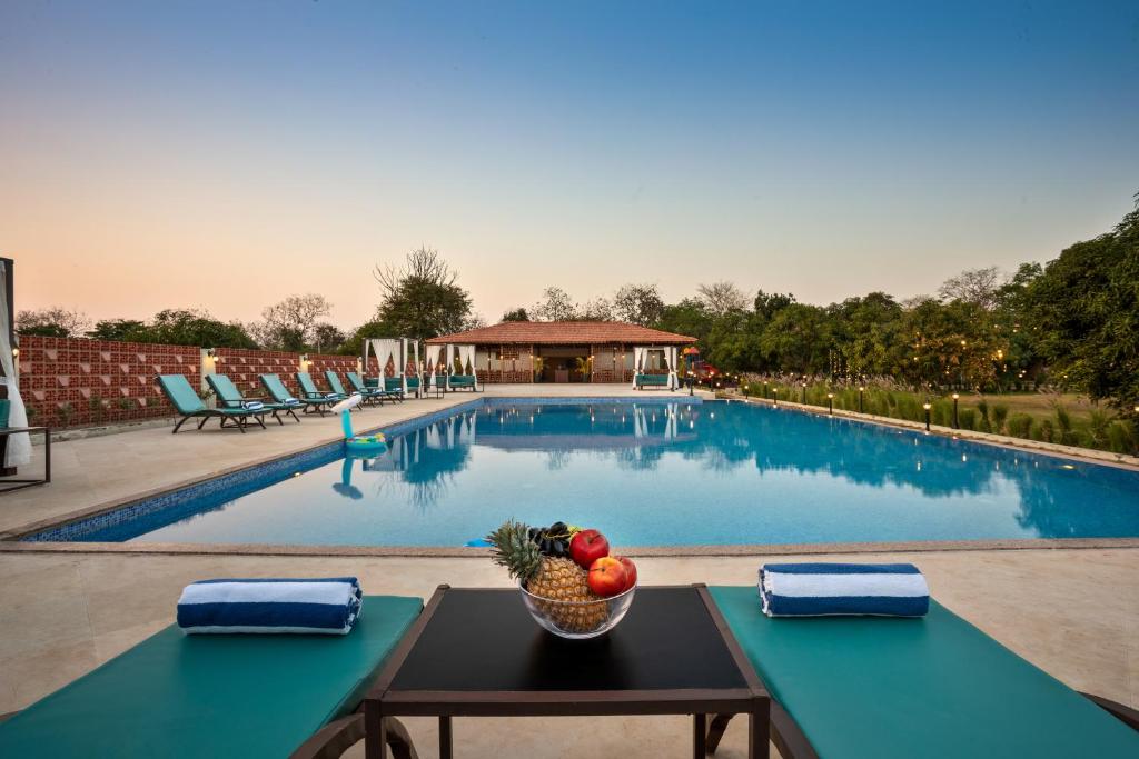 a bowl of fruit on a table in front of a swimming pool at The Vanveda Resort By Nirvana in Sasan Gir