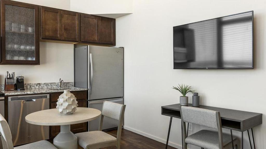 cocina con mesa y nevera de acero inoxidable en Landing Modern Apartment with Amazing Amenities (ID1178X938) en Omaha