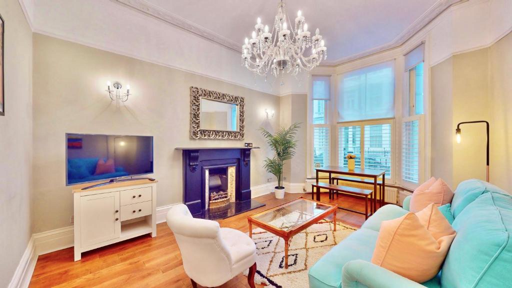 ein Wohnzimmer mit einem blauen Sofa und einem Kamin in der Unterkunft Bright & Spacious West London Gem in London