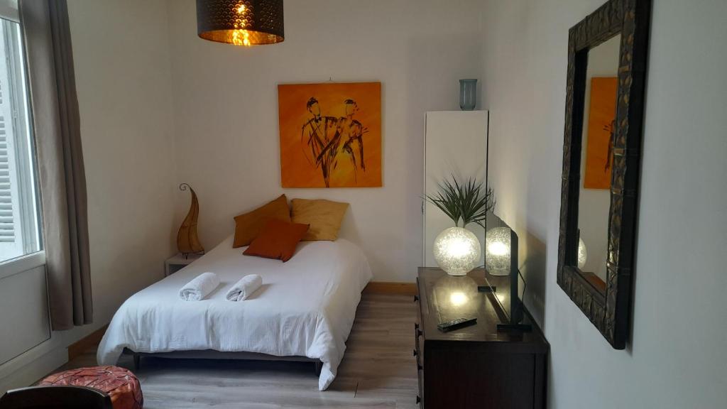 een slaapkamer met een wit bed en een spiegel bij Chez Eric le n2 in Tours