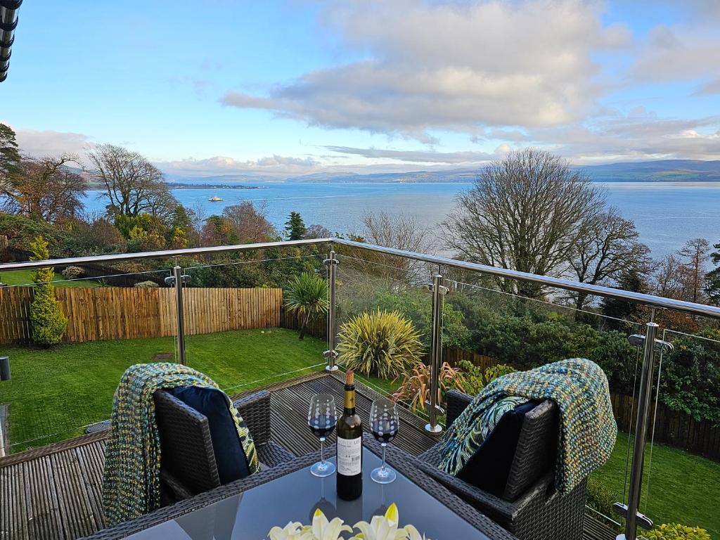 a table and chairs on a balcony with a view of the water at Viewpoint Villa - Luxury 4 Bedroom villa with elevated views in Rothesay