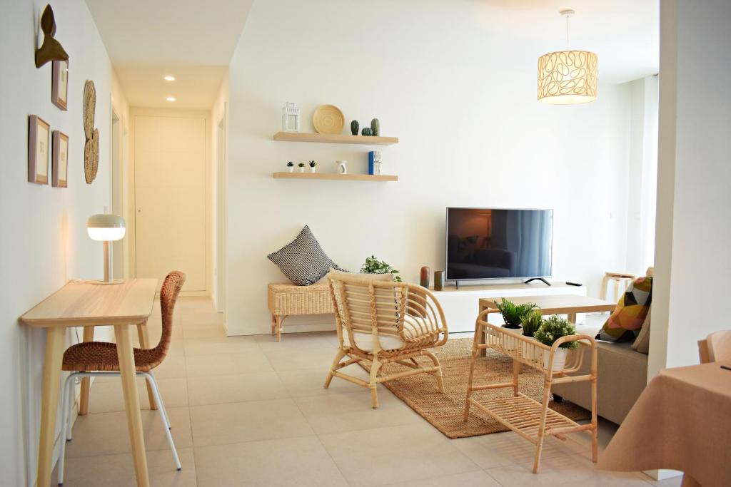 sala de estar con sillas, mesa y TV en Amalia's Home: Luminoso apartamento muy cerca de la playa, en Málaga