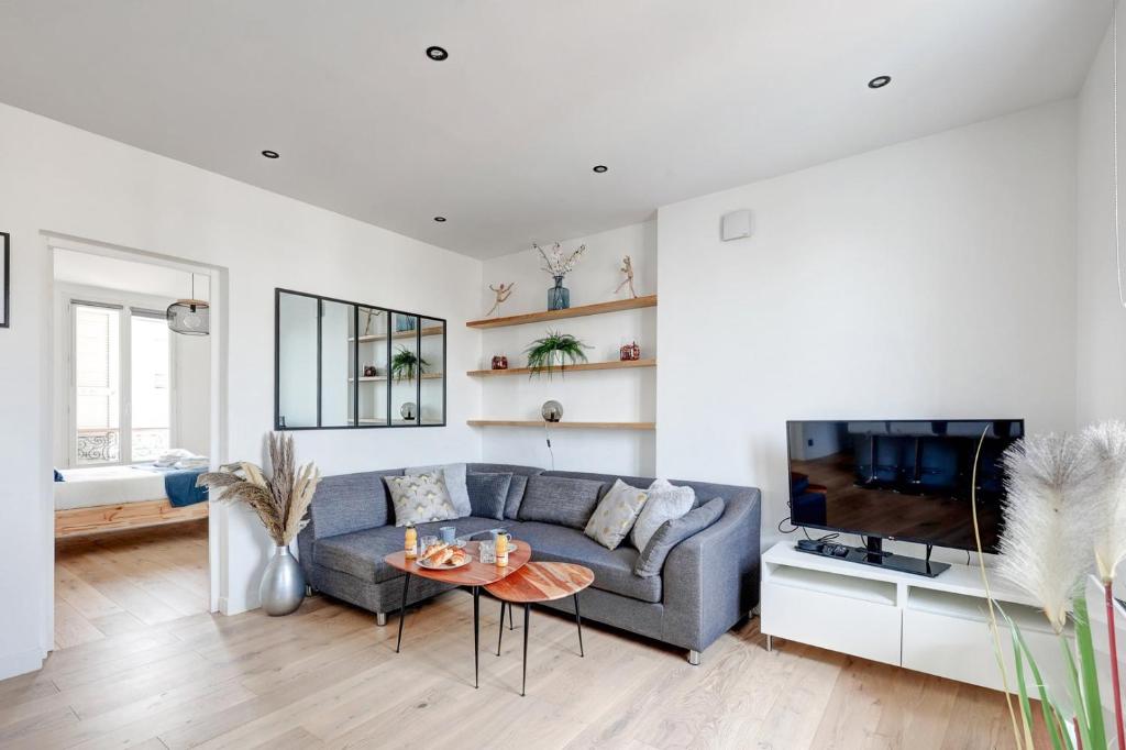 een woonkamer met een blauwe bank en een tv bij 341 Suite Modern Art - Superb Apartment in Paris in Suresnes