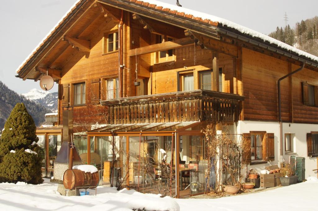 Casa de madera grande con nieve en el suelo en Beat & Ursula's Guest House en Jenaz