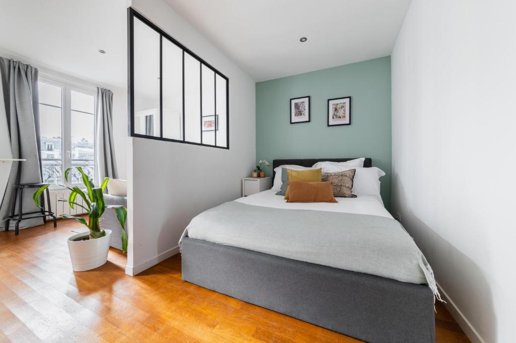 une chambre avec un grand lit aux murs bleus dans l'établissement Cosy Apt Batignoles, à Paris