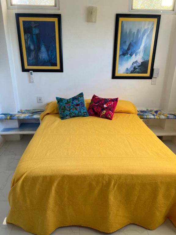 ein Schlafzimmer mit einem gelben Bett mit zwei Kissen darauf in der Unterkunft Amarilla (Amar y ya) in Cuatunalco