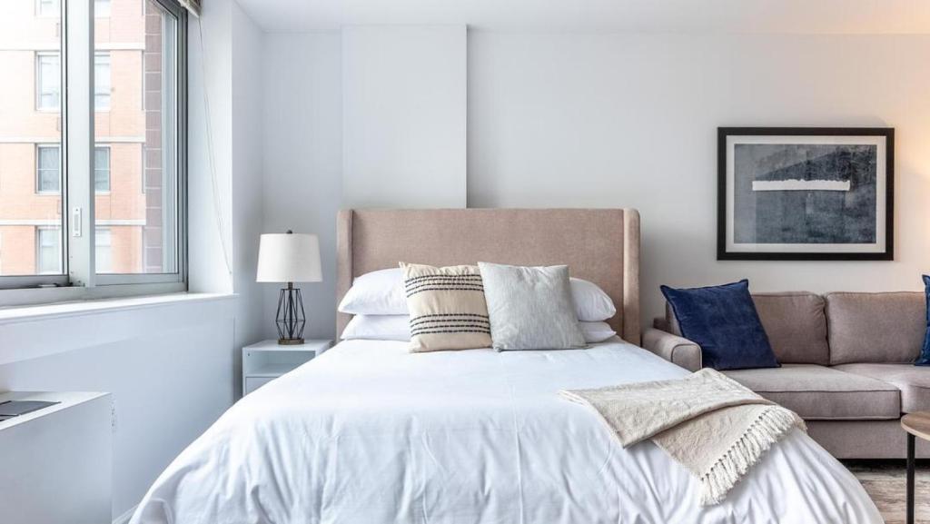 - une chambre blanche avec un lit et un canapé dans l'établissement Landing - Modern Apartment with Amazing Amenities (ID5067X83), à New York