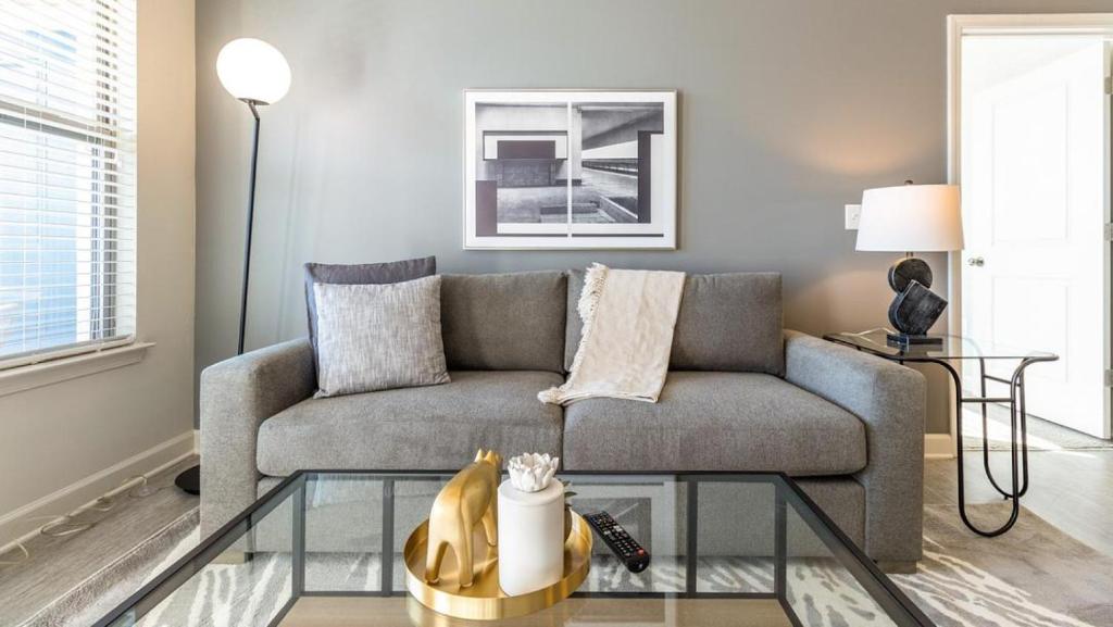 un soggiorno con divano e tavolo in vetro di Landing - Modern Apartment with Amazing Amenities (ID8251X95) a Wake Forest
