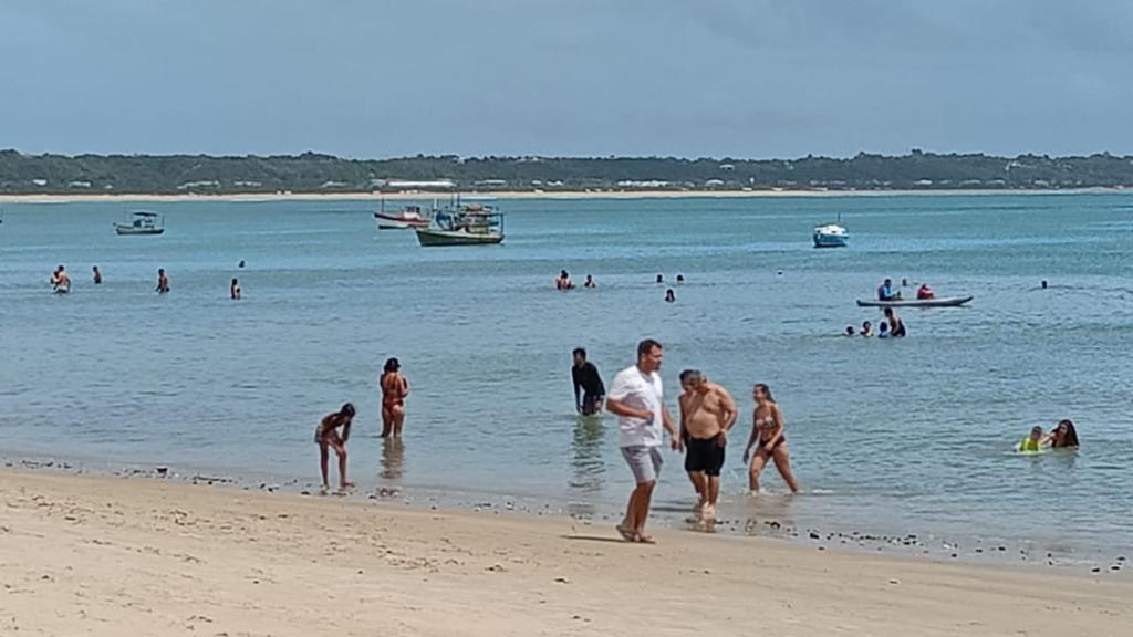 grupa ludzi w wodzie na plaży w obiekcie Ytamãní ll apartamentos w mieście Santa Cruz Cabrália