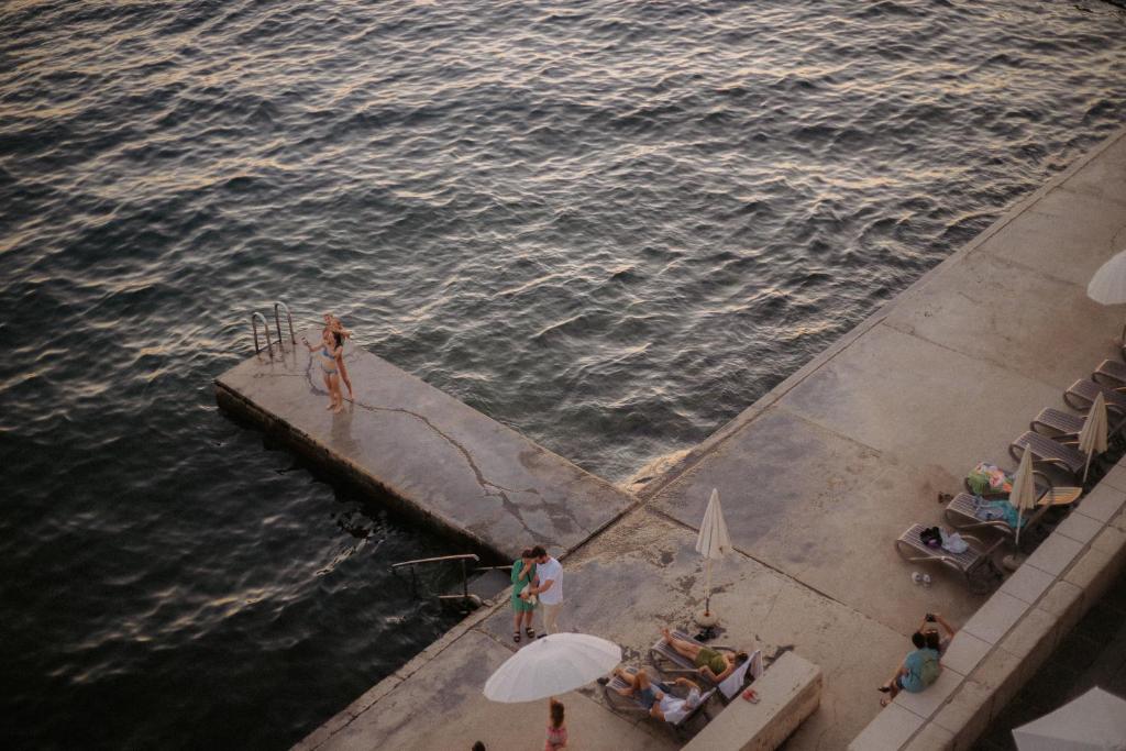 a couple of people on a dock in the water at Hotel Piran in Piran