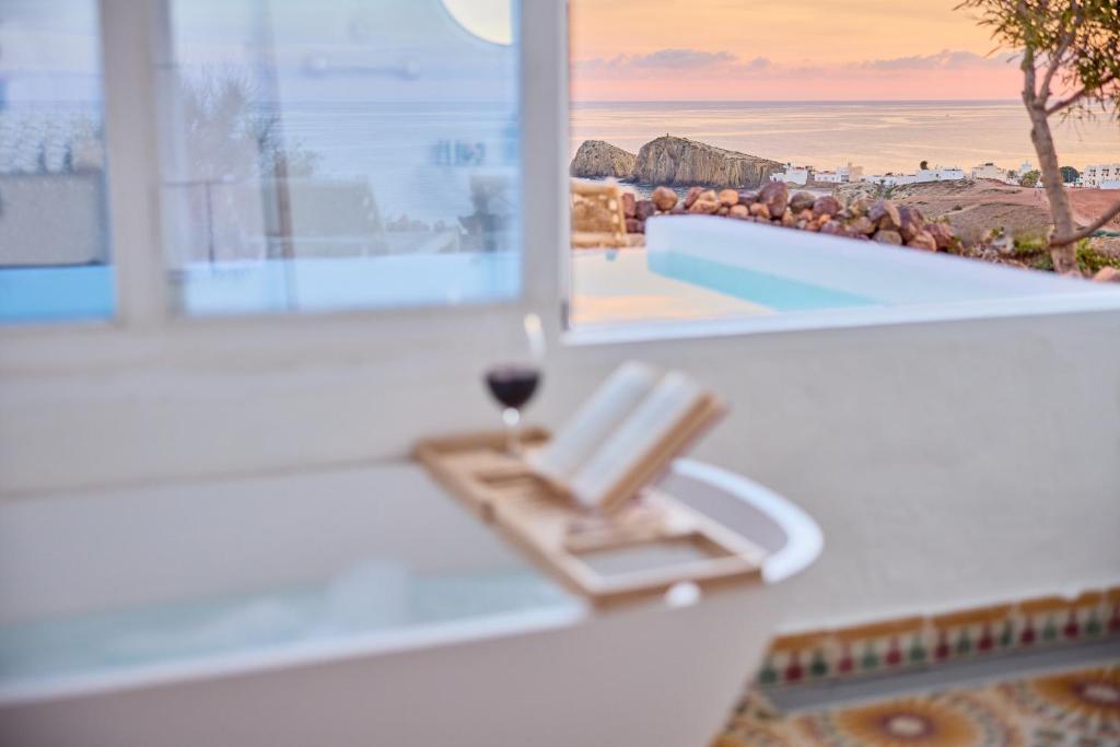 une chaise de plage avec un verre de vin à côté d'une fenêtre dans l'établissement Cortijo La Loma, à La Isleta del Moro