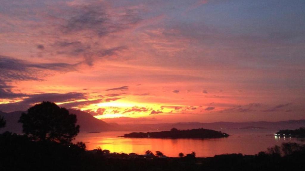 einen Sonnenuntergang über einem Wasserkörper mit einer Insel in der Unterkunft Valentina 24 HORAS in Florianópolis
