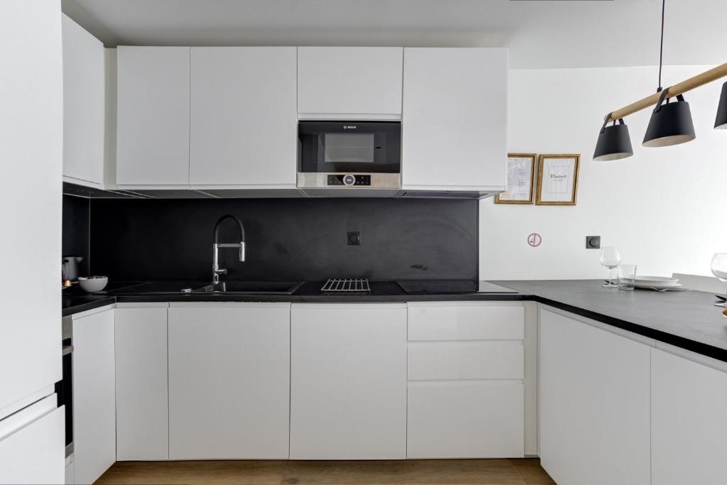 a white kitchen with white cabinets and a sink at 322 Suite Fes - Superb apartment in Suresnes
