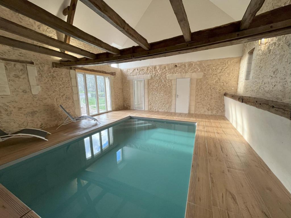 a large swimming pool in a room with wooden floors at Les gîtes de La Pellerie - 2 piscines &amp; spa Jacuzzi - Touraine - 3 gîtes - familial, calme, campagne in Saint-Branchs