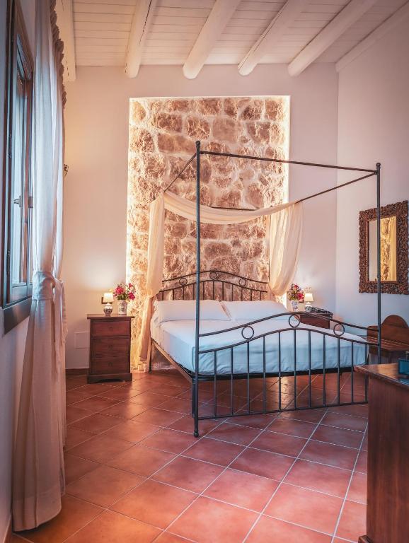 a bedroom with a bed and a stone wall at Hotel La Corte Del Sole in Noto