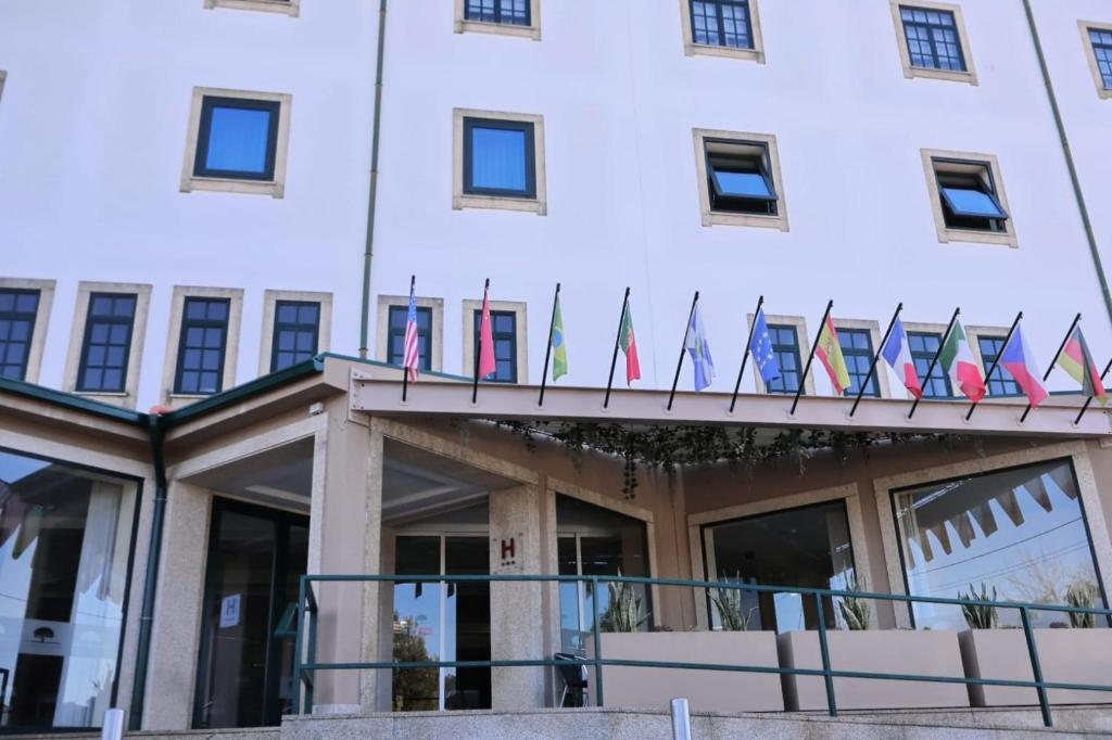 une rangée de drapeaux à l'avant d'un bâtiment dans l'établissement HOTEL SANTHYAGO TROFA, à Trofa