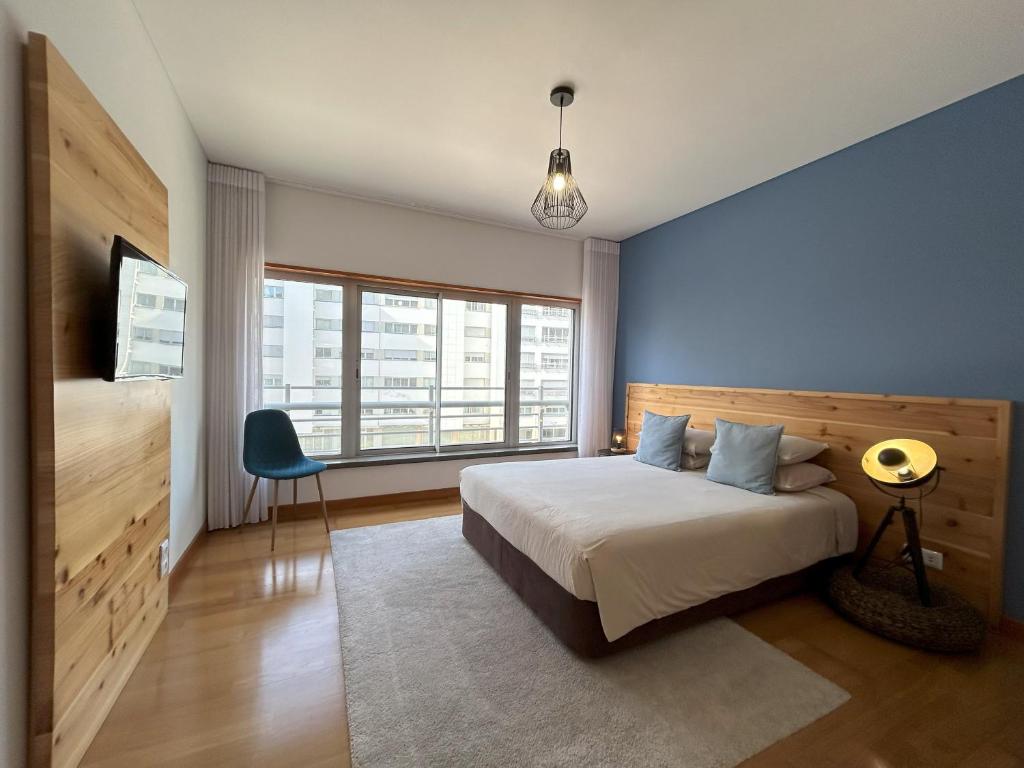 um quarto com uma cama e uma parede azul em Oceanus Executive em Ponta Delgada