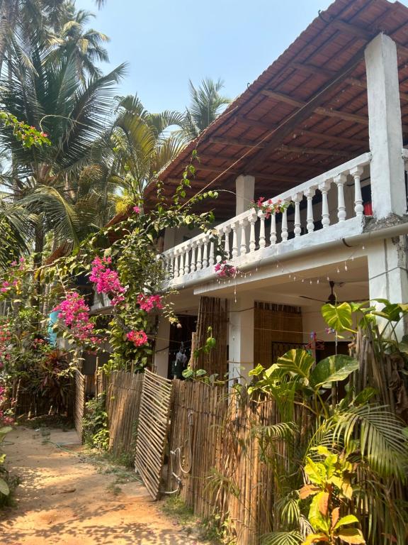 Una casa con una valla y flores rosas. en Palm Breeze Villas, en Palolem