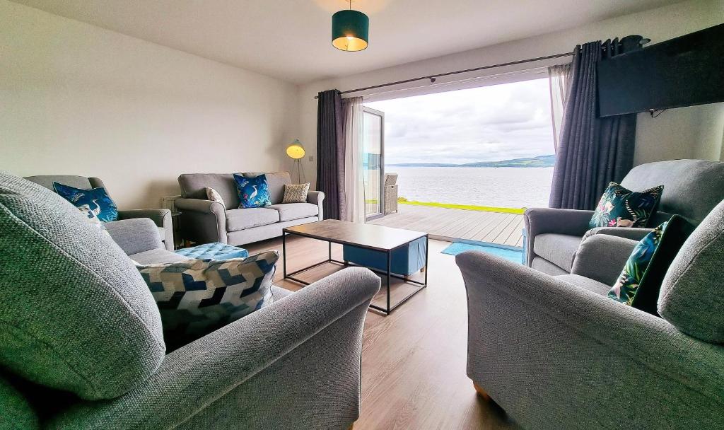 una sala de estar con sofás y vistas al agua. en Shoreside Villa - immaculate waterfront property in Skelmorlie, en Skelmorlie