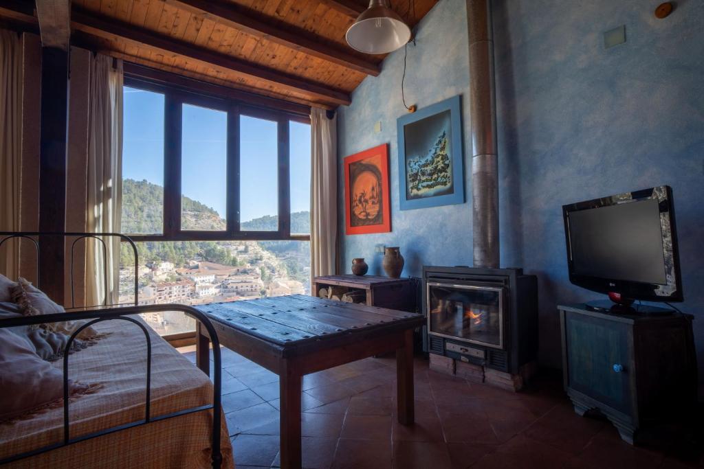 sala de estar con mesa, TV y chimenea en Casa Rural Los Ventanales, en Alcalá del Júcar