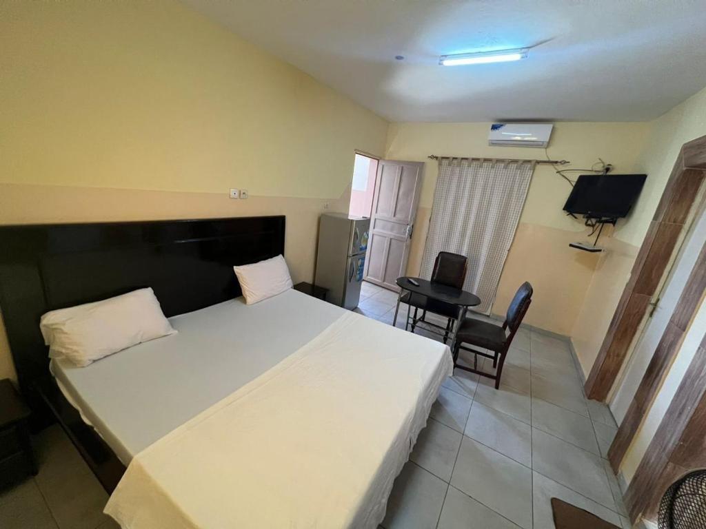 1 dormitorio con 1 cama blanca grande y escritorio en Chez Mimi, en Toubab Dialaw