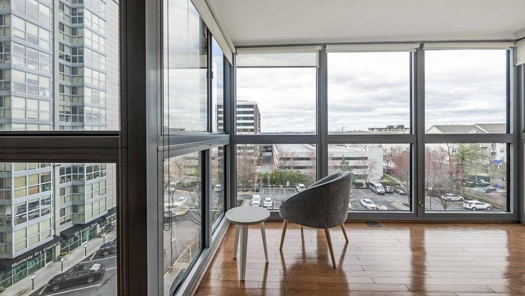 une chaise assise dans une pièce avec fenêtres dans l'établissement Landing - Modern Apartment with Amazing Amenities (ID1316X116), à Bethesda