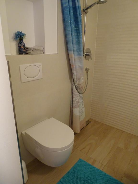 uma casa de banho com um WC branco e um chuveiro em Ferienwohnung am Pilsensee em Seefeld