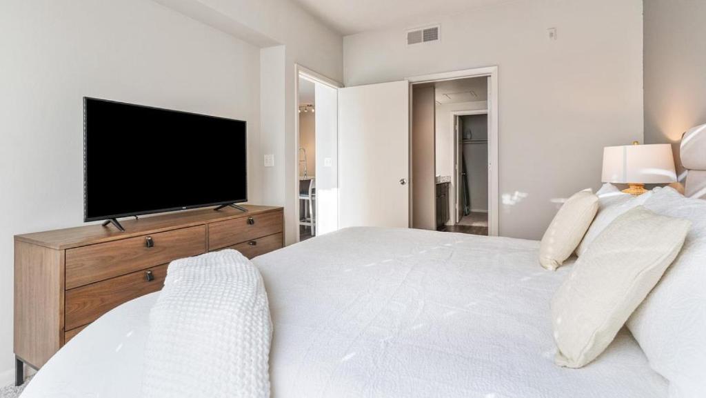 a white bedroom with a large bed and a television at Landing - Modern Apartment with Amazing Amenities (ID7779X23) in Austin