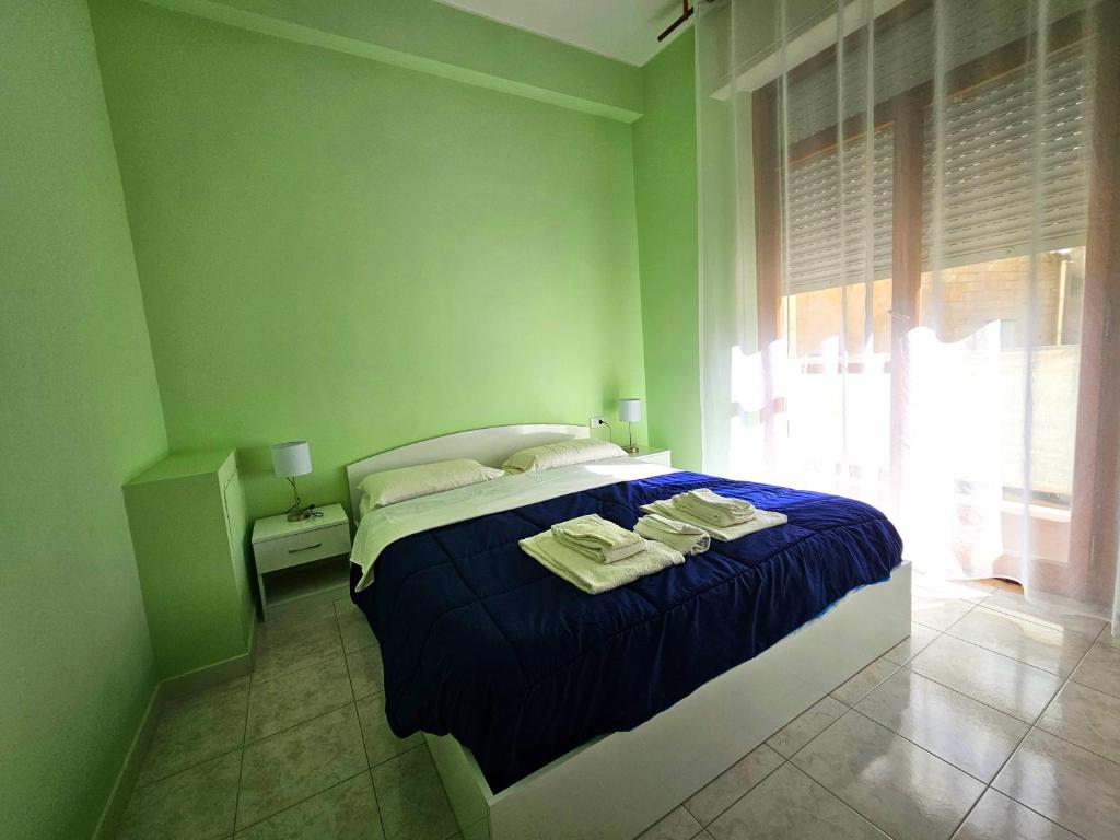een groene slaapkamer met een bed met handdoeken erop bij Mammasisi Rooms in Lecce