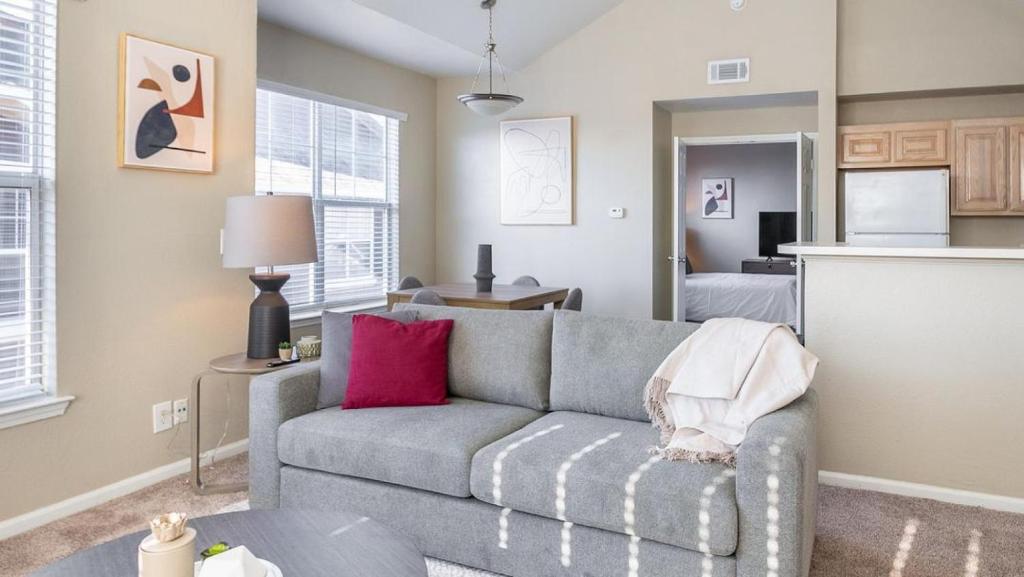 a living room with a gray couch and a kitchen at Landing - Modern Apartment with Amazing Amenities (ID8246X10) in Tulsa