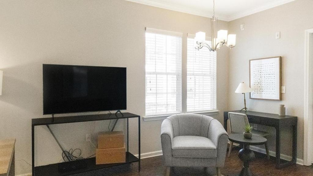 ein Wohnzimmer mit einem Flachbild-TV und einem Stuhl in der Unterkunft Landing - Modern Apartment with Amazing Amenities (ID2396X34) in Baton Rouge
