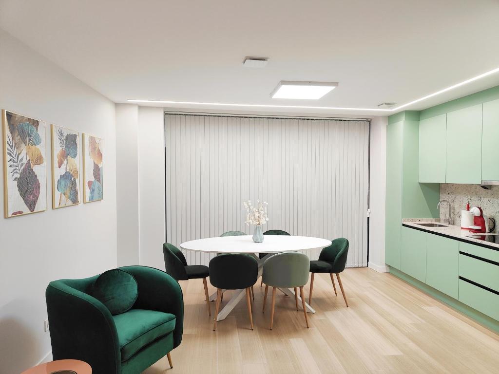 a dining room with a white table and green chairs at ELEGANCIA Y MODERNIDAD EN PLENO CENTRO in Oviedo