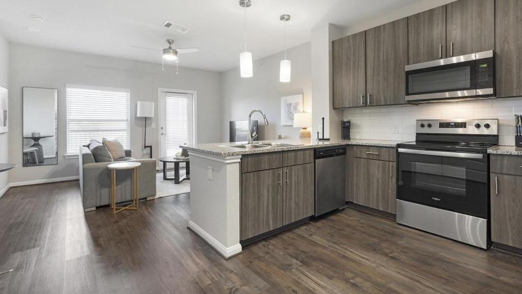 uma cozinha com utensílios de aço inoxidável e armários de madeira em Landing - Modern Apartment with Amazing Amenities (ID7253X29) em San Antonio