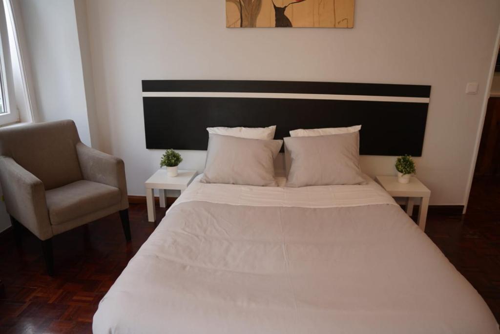 - une chambre avec un grand lit blanc et une chaise dans l'établissement Bisengototo Homestay, à Lisbonne