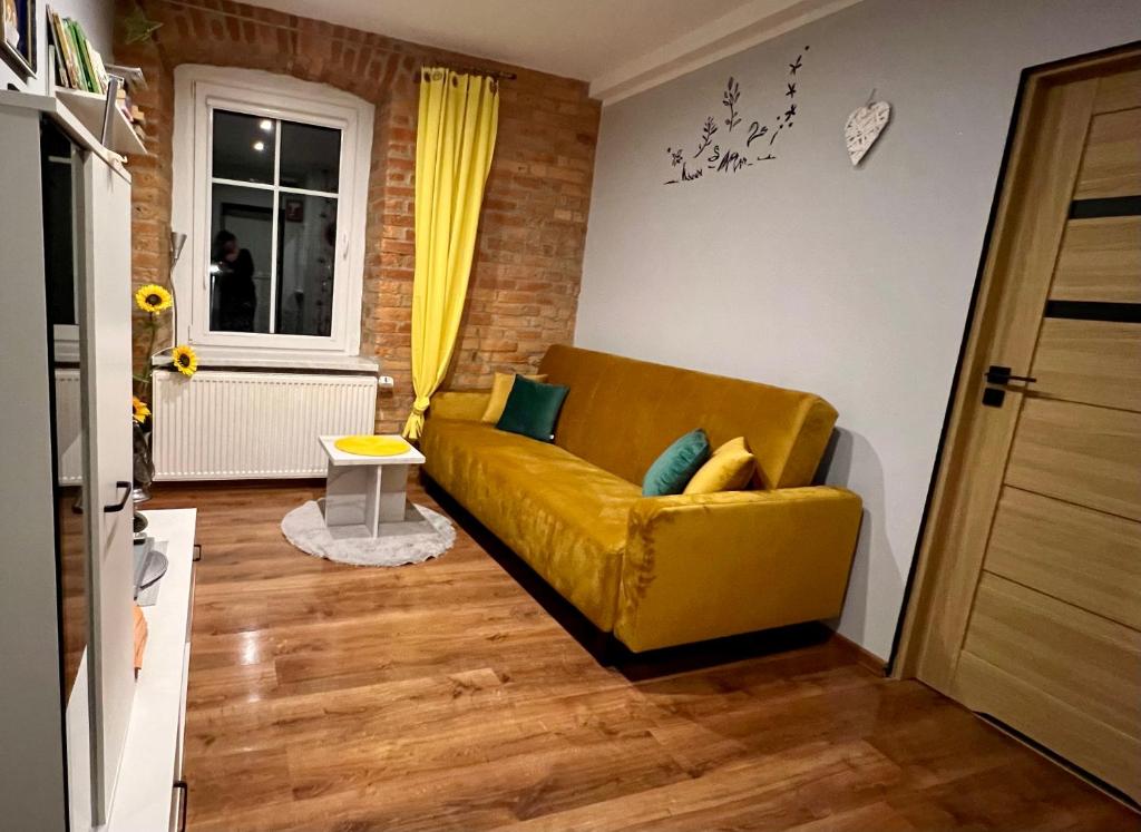 a living room with a yellow couch and a window at Apartament u Kasi in Świeradów-Zdrój