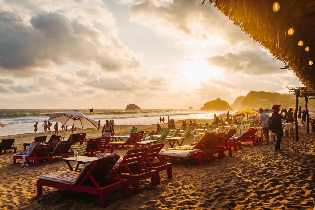 a beach with chairs and people on the sand at Che Zipolite Hostel & Naked Beach Club in Zipolite